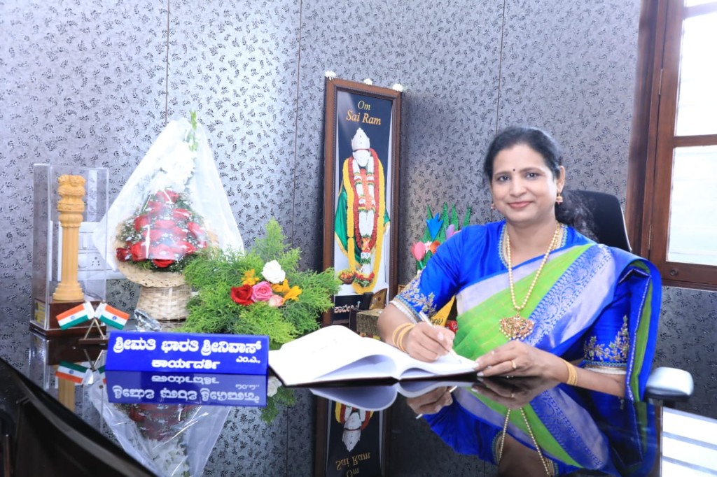 Smt. Bharathi Srinivas, Secretary, seated at her office desk with school honours and flowers